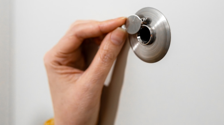 Person moving the cover aside on the peephole