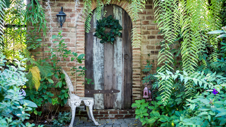 A wreath on an old wooden door in a vibrant green garden