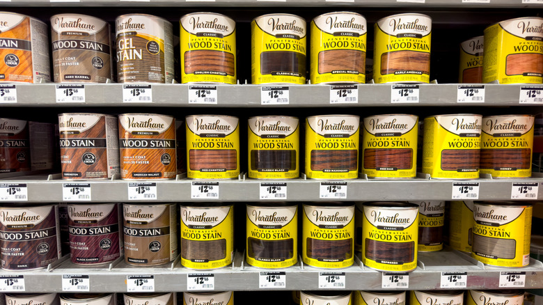 Cans of wood stain in various colors on a store shelf