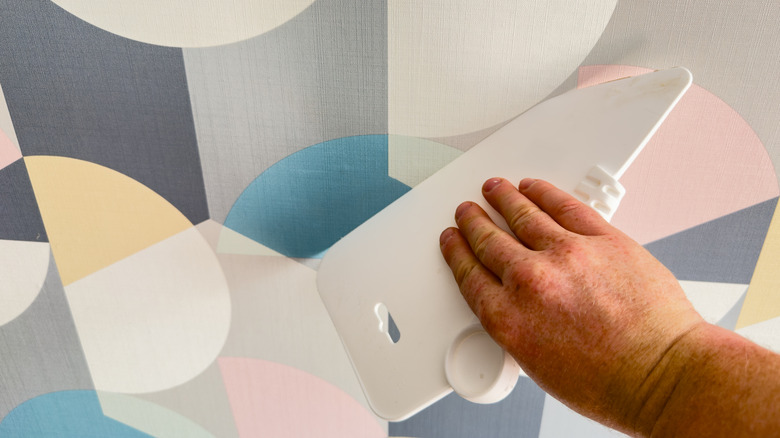 Person smoothing out wallpaper on a wall