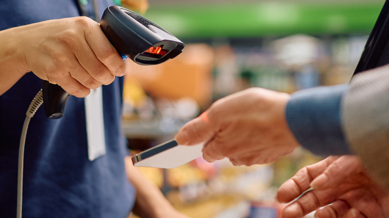 Cashier scanning a coupon on a person's phone.