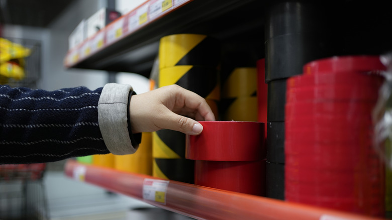 Hand reaching for red tape on store shelf