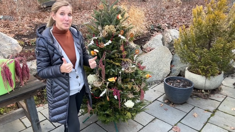 Woman standing beside a decorated Christmas tree in yard