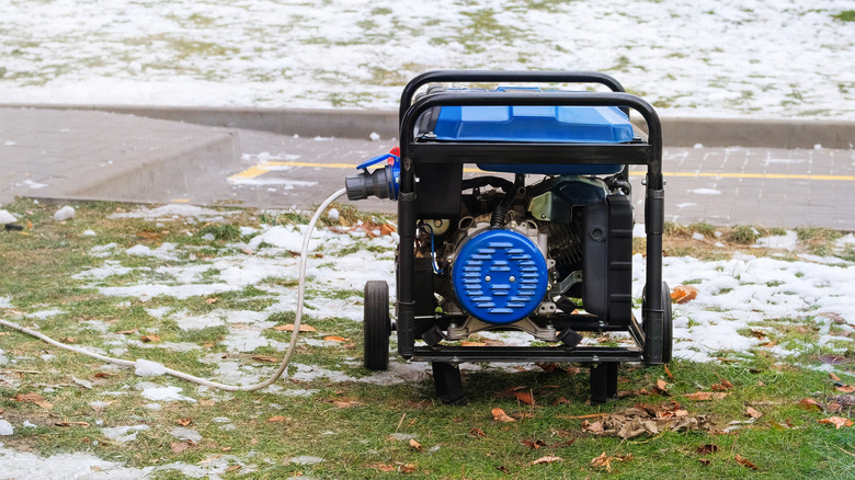 A blue portable generator sitting outside with snow on the ground