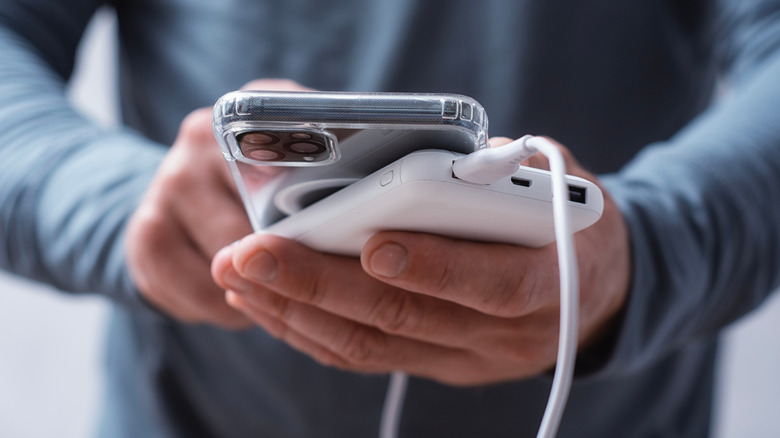 Person holding a cell phone connected to a portable charger
