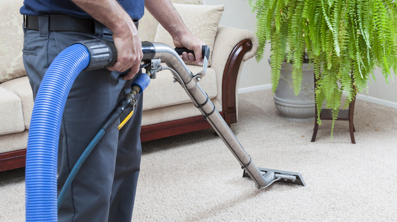 A professional is steam cleaning white carpets in a home