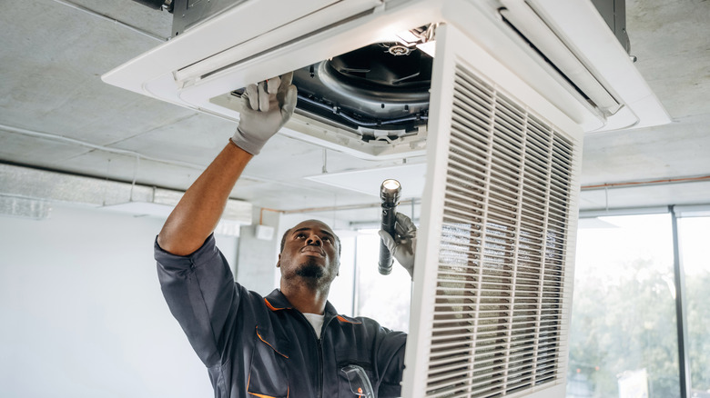A repairman looks at a broken vent