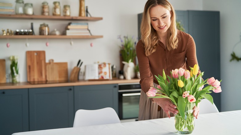 A lady putting flowers in a vase 
