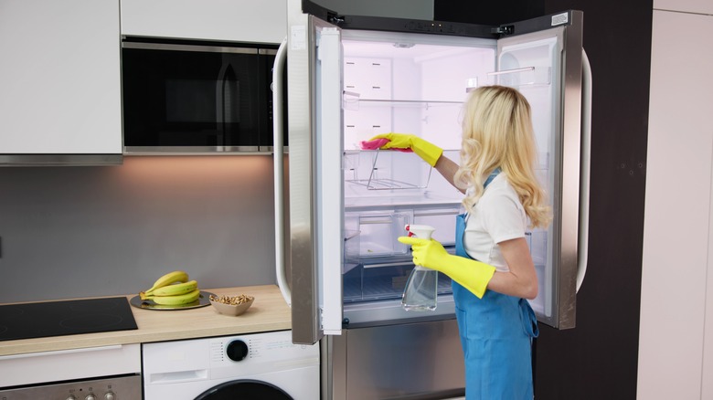 A lady cleaning a refrigerator 