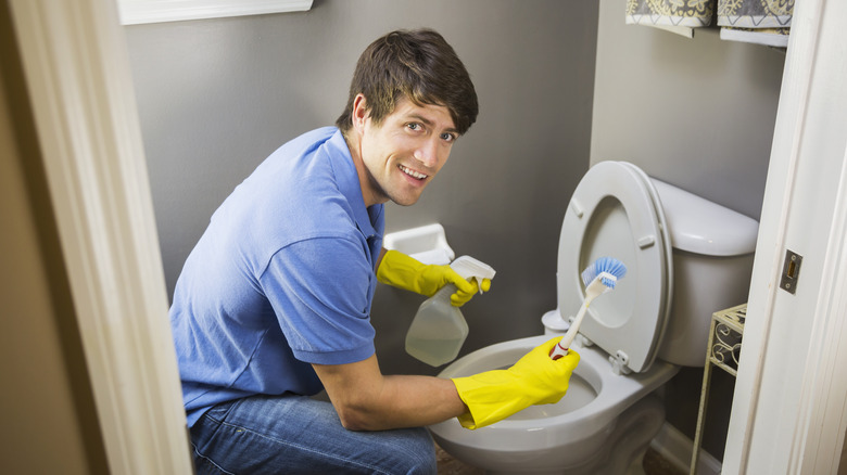 A man cleaning the toilet 