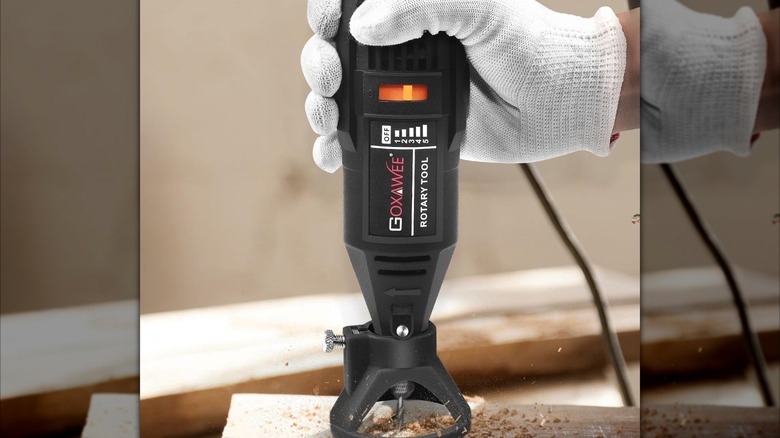 A gloved hand drilling wood with HYCHIKA's Variable Speed Rotary Tool