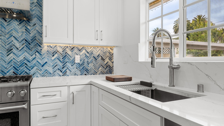 Blue mosaic backsplash in an otherwise white kitchen