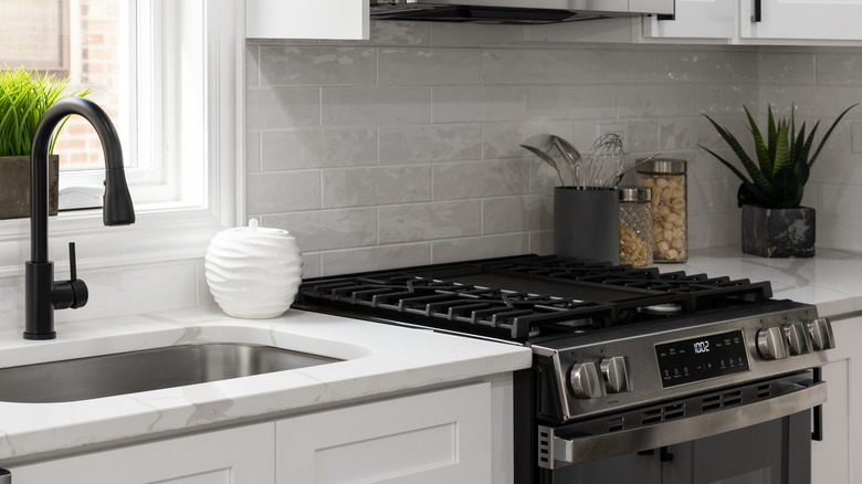 A gray backsplash in a kitchen with a stainless steel stove