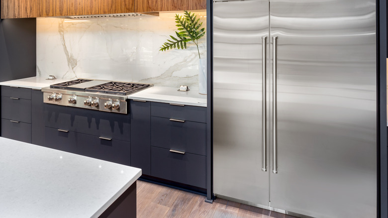 A white marble slab backsplash with gray veining in a kitchen with navy cabinets