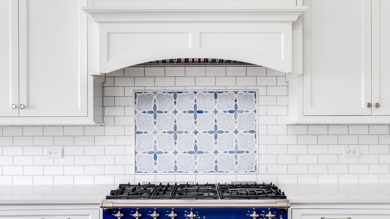 A white backsplash with a blue mosaic above the stove
