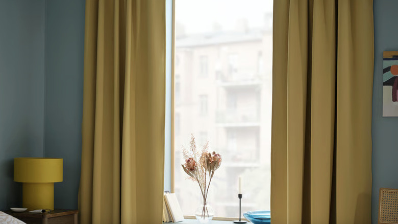 The MAJGULL Room darkening curtains from IKEA hanging in a bedroom with turquoise walls.
