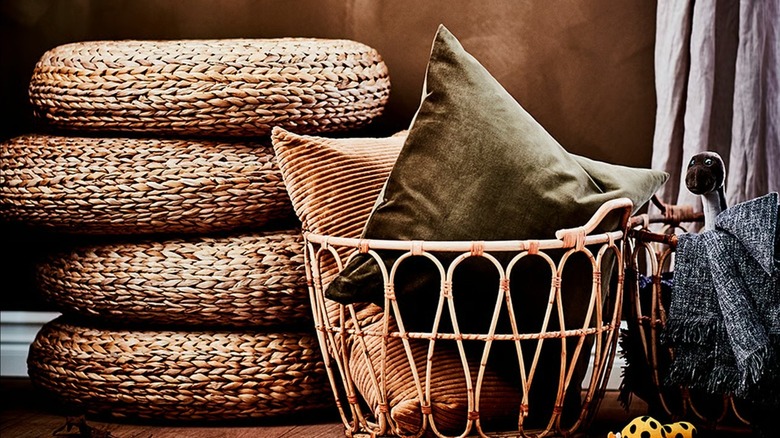 Pile of ALSEDA Banana Fiber Stools next to basket of full of pillows