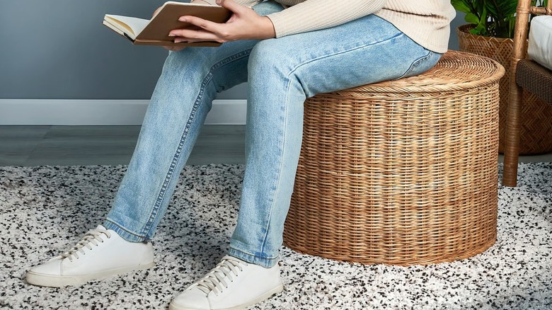 Person sitting on TOLKNING Ottoman with storage