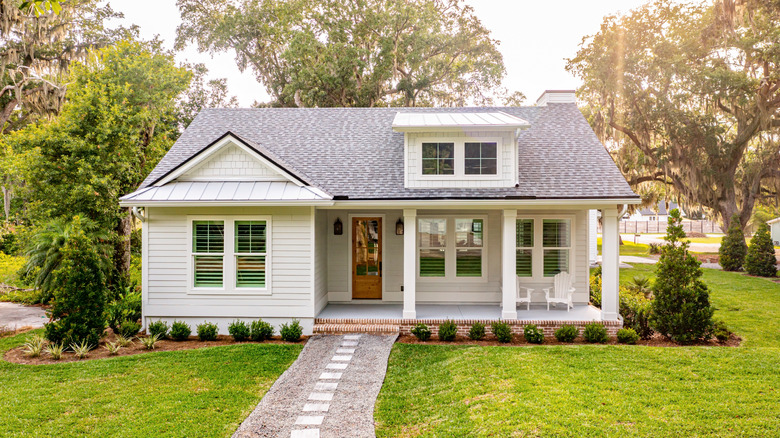 White house with a simple front porch surrounded by trees