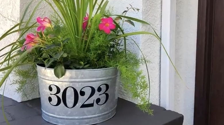 Planter customized with street address filled with greenery and pink flowers