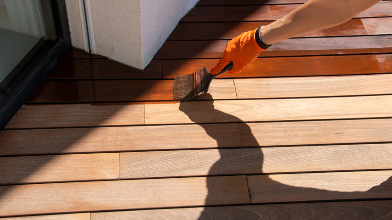 Person applying stain to a wood deck floor