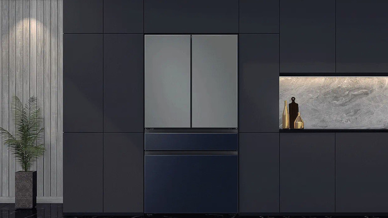 Charcoal and navy blue Samsung refrigerator in a modern kitchen with navy blue cabinets and grey accents