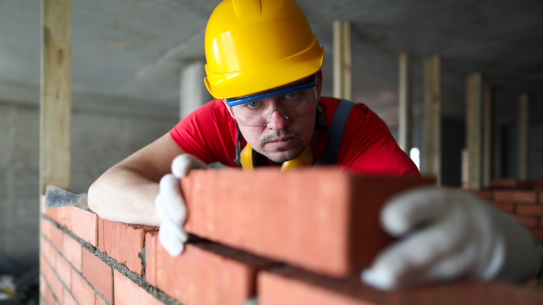 man placing brick on wall