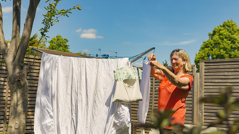 Person hanging bed sheets to dry