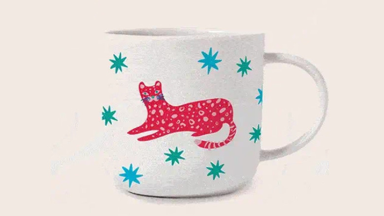 A mug with a big pink cat on it and blue stars