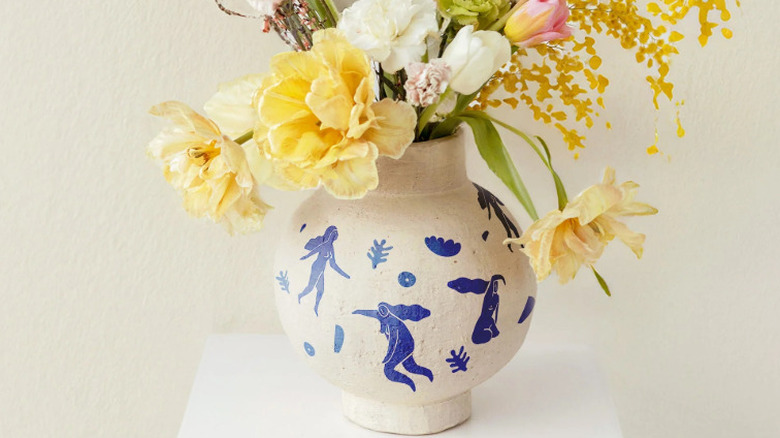A vase full of flowers with blue decal tattoos