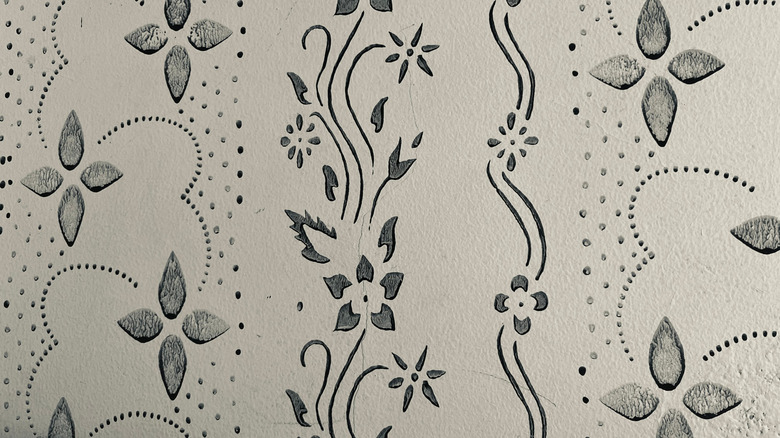A plain white wall with black floral patterns