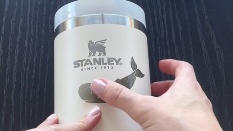 A whale tattoo being applied to a Stanley cup