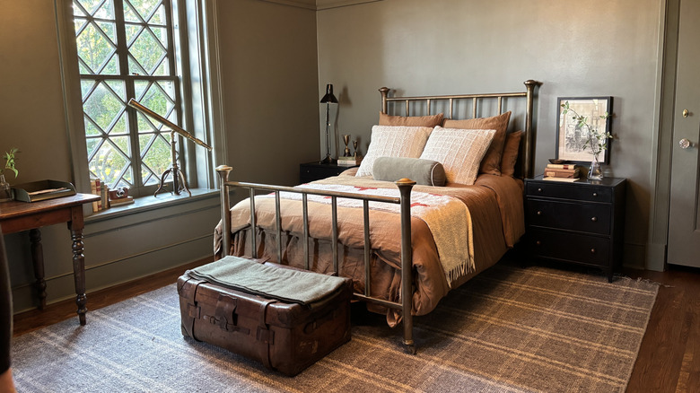 Vintage-style room with bed, traveling trunk, telescope, and portrait