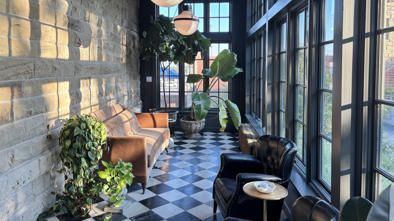 Conservatory with checkered floor, leather couch, and many plants