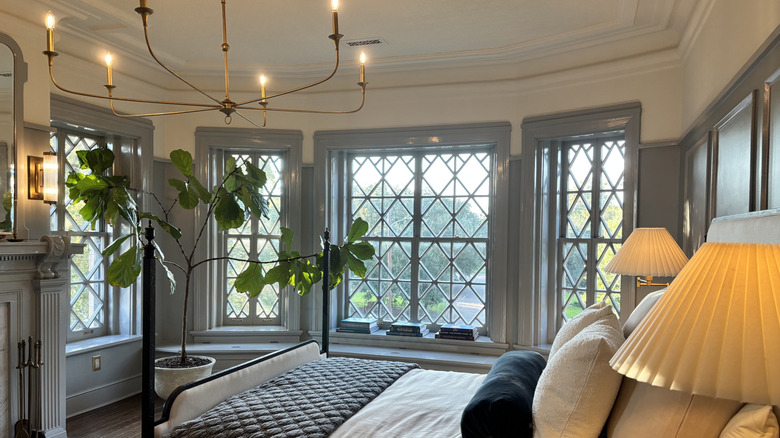 A bedroom with many windows and a wiry candelabra chandelier