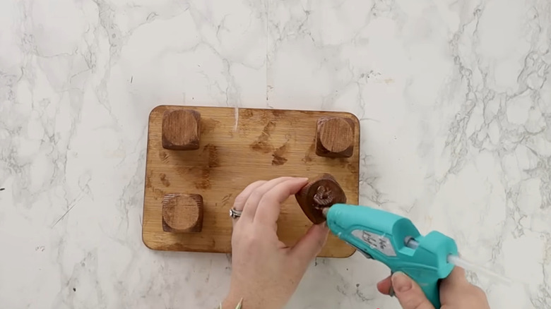 Woman hot gluing wood countertop riser over stone countertop