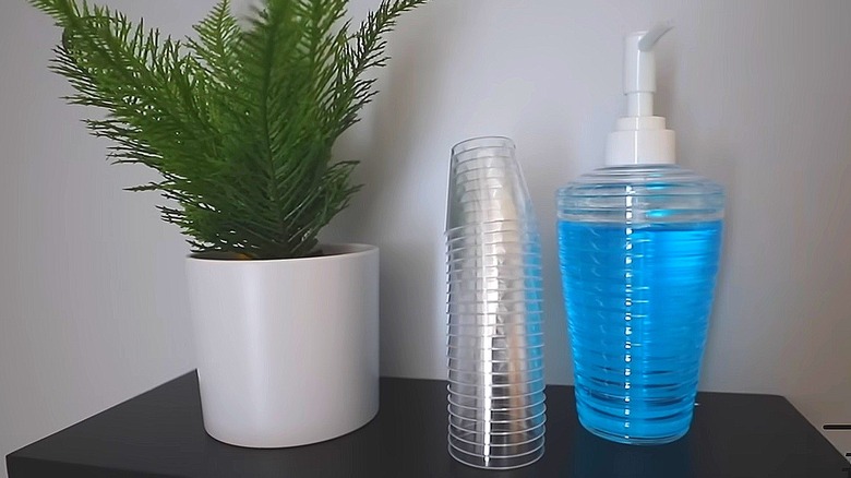 Mouthwash and shot glass station beside potted plant