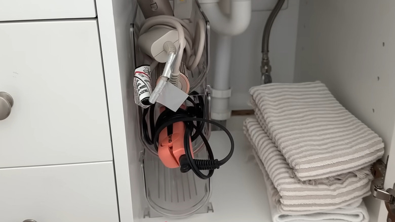 Stacked wine bottle holders under bathroom sink with hair styling tools