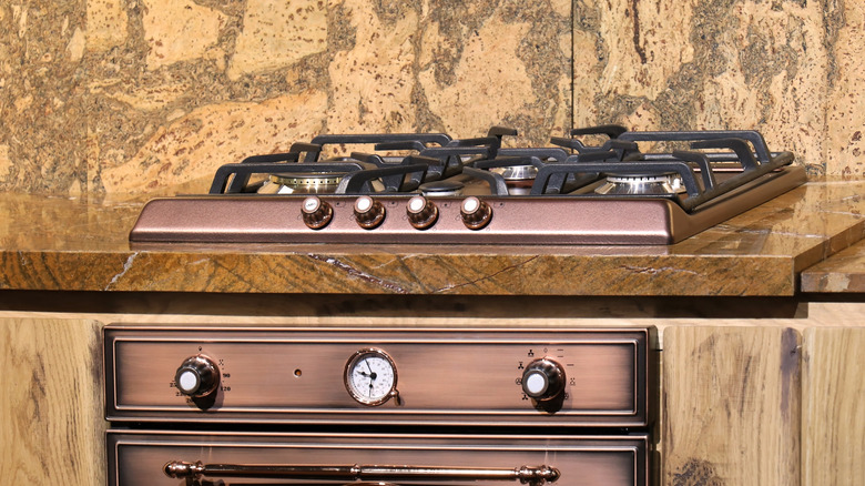 A bronze oven range in a yellow marble countertop.