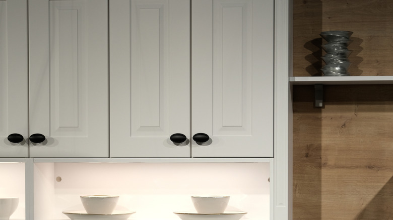 Shaker-style white cabinet doors next to natural wood built-in shelving