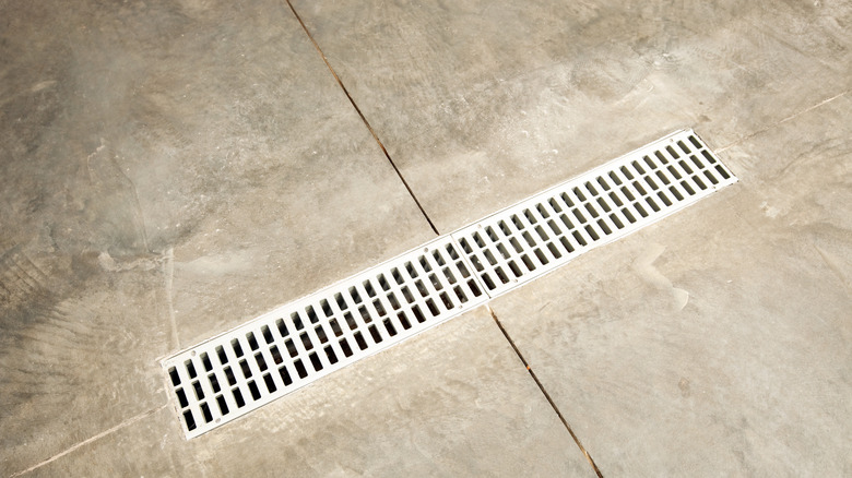 A long, rectangular drain built into the concrete floor of a garage