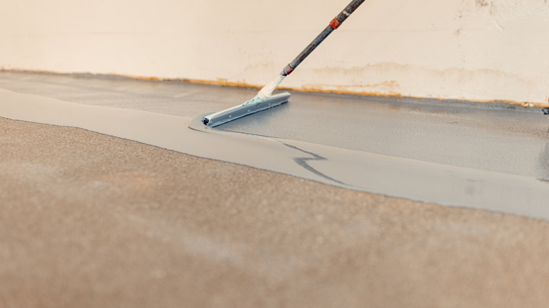 Person applying an epoxy coating to a plain garage floor
