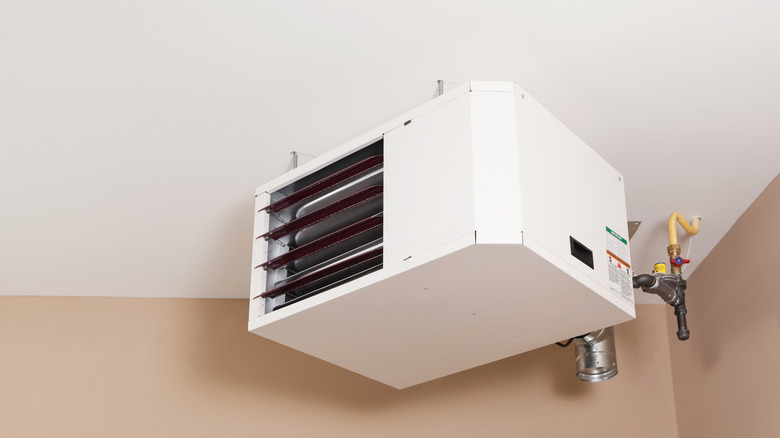 White heating unit mounted to the ceiling of a garage