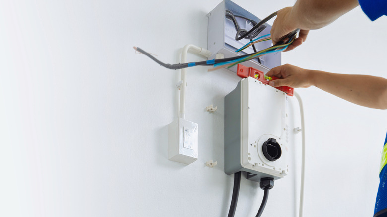 Electrician installing an EV charger in a home on a white wall