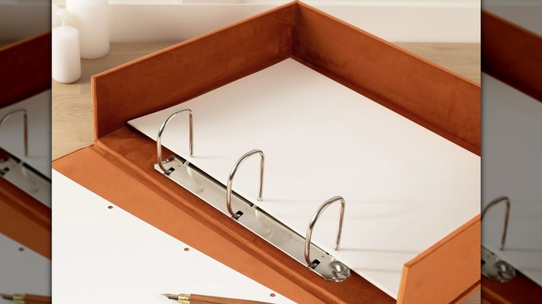 an opened tan three ring binder box with paper on the inside