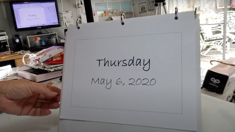 someone holding a white flip calendar