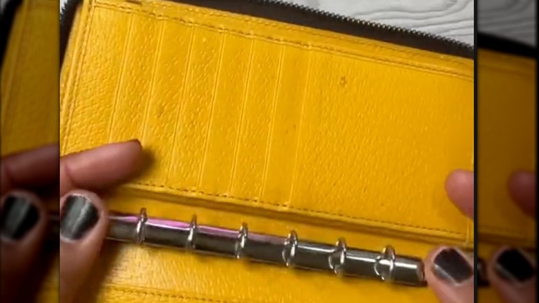 someone placing a small binder spine into a yellow wallet