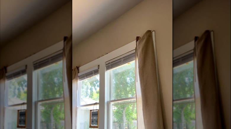 binder spines at top of window holding tan curtains