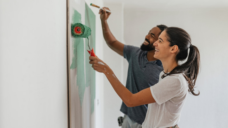 A happy couple painting a wall together