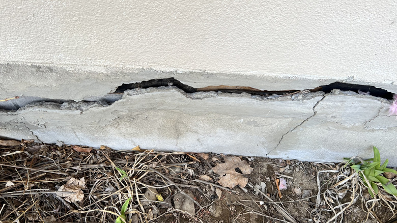 A wide crack runs through a house foundation